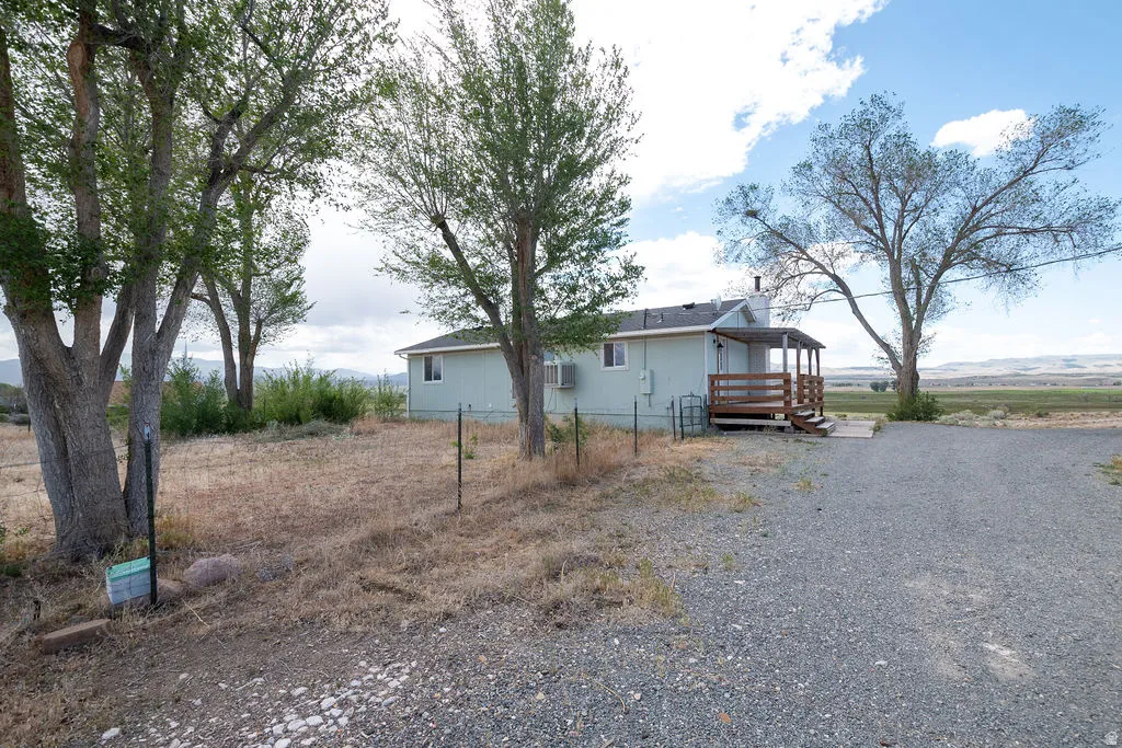 Single-story residence featuring a light-colored exterior siding, a covered wood-finish porch, and a gravel driveway