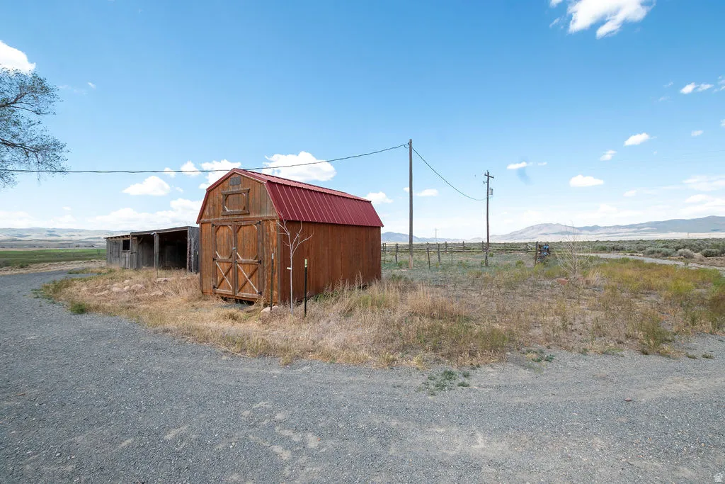 Gravel driveway leading to a wood-sided outbuilding with a red metal roof