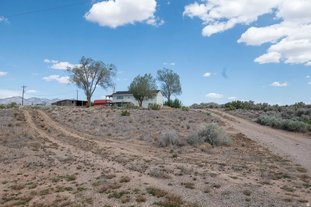 Expansive desert landscape with a single-family residence featuring a raised foundation, a broad balcony, and a white exterior