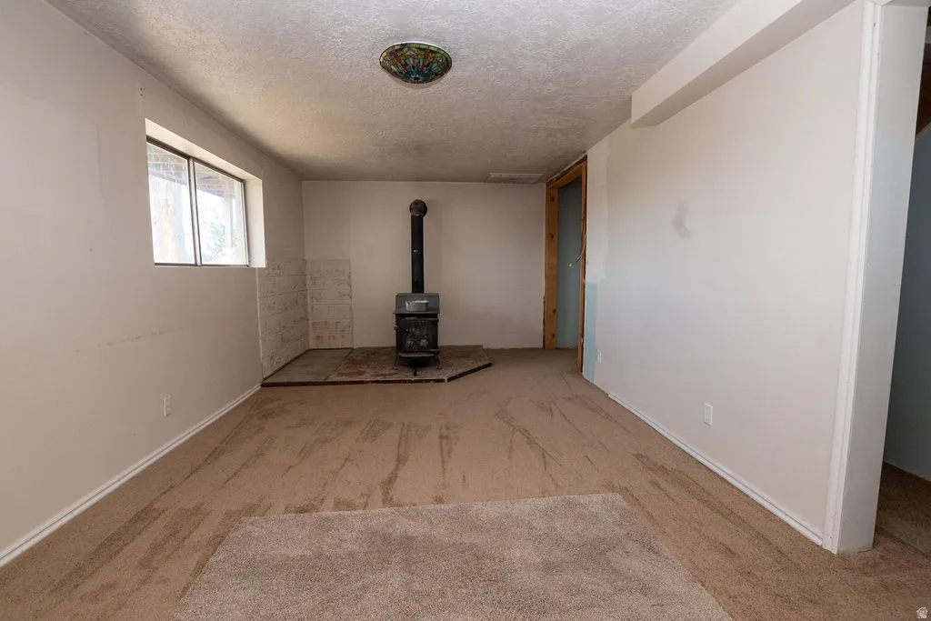 Living area featuring a wood-burning stove with a tile hearth and a window providing natural light