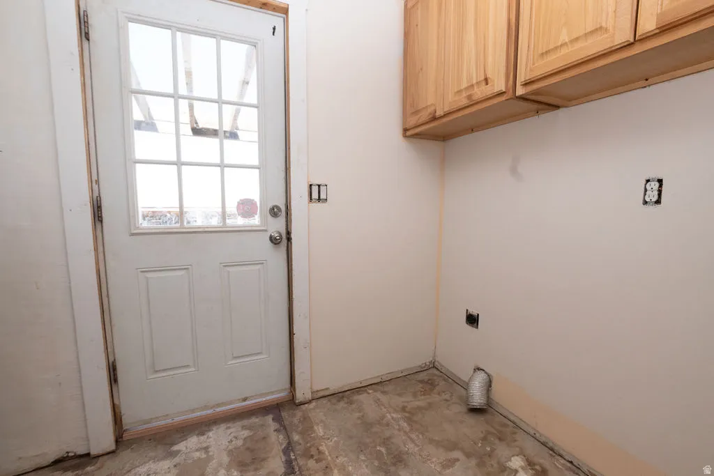 Utility space featuring a glass-paneled exterior door, overhead wood cabinetry, and exposed electrical outlets
