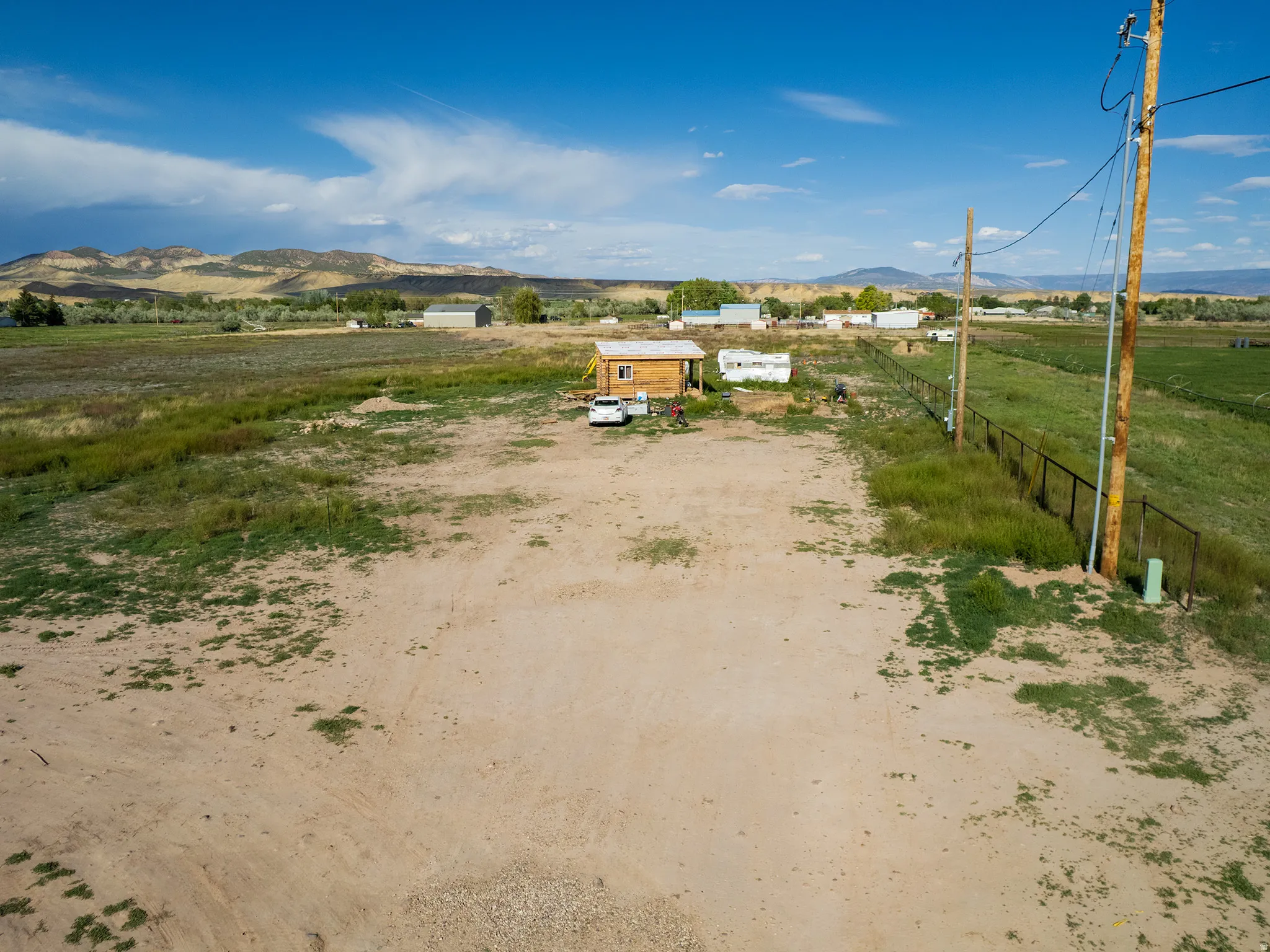 Expansive lot featuring a small cabin structure and a surrounding rural landscape