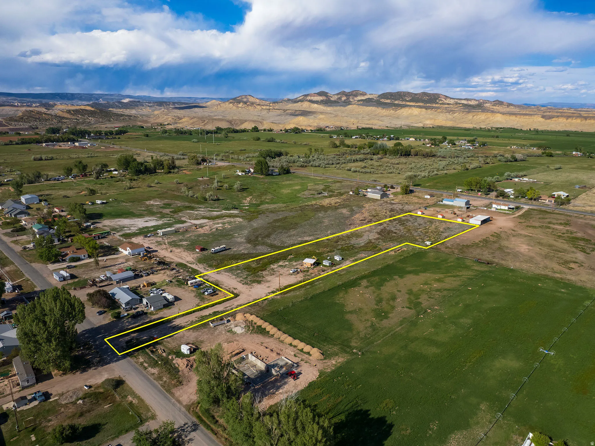 Expansive undeveloped land featuring a defined perimeter, direct road access, and proximity to agricultural fields