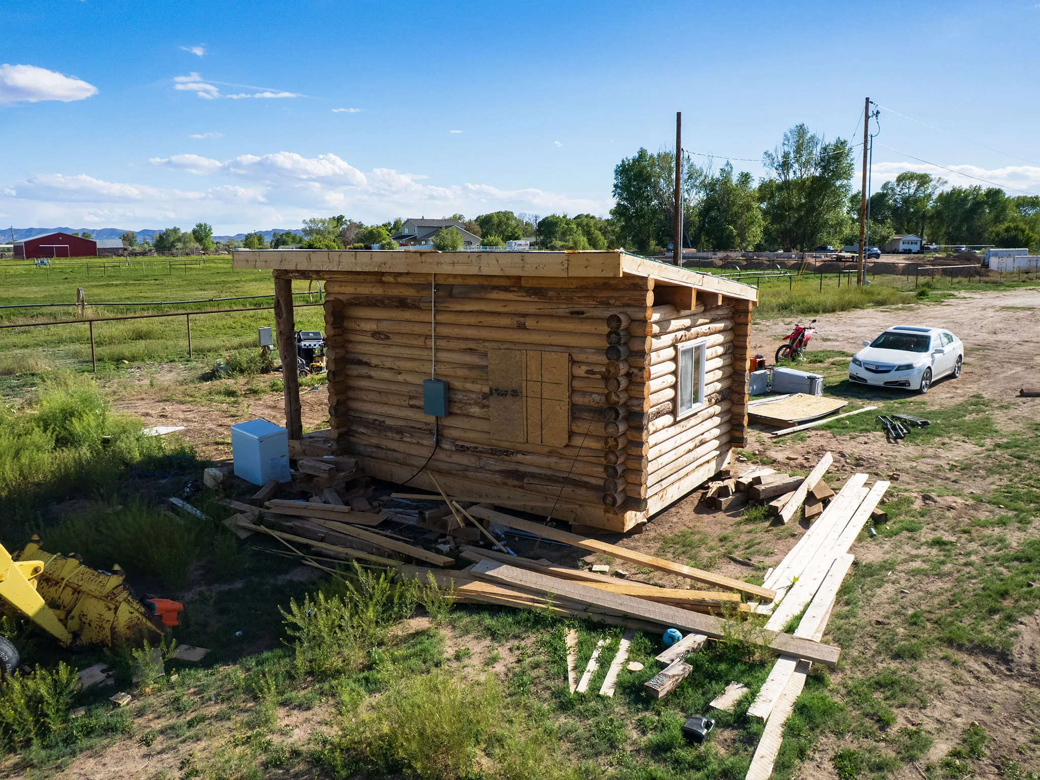 Log cabin structure featuring exposed log construction, a rectangular window opening, and a flat roofline