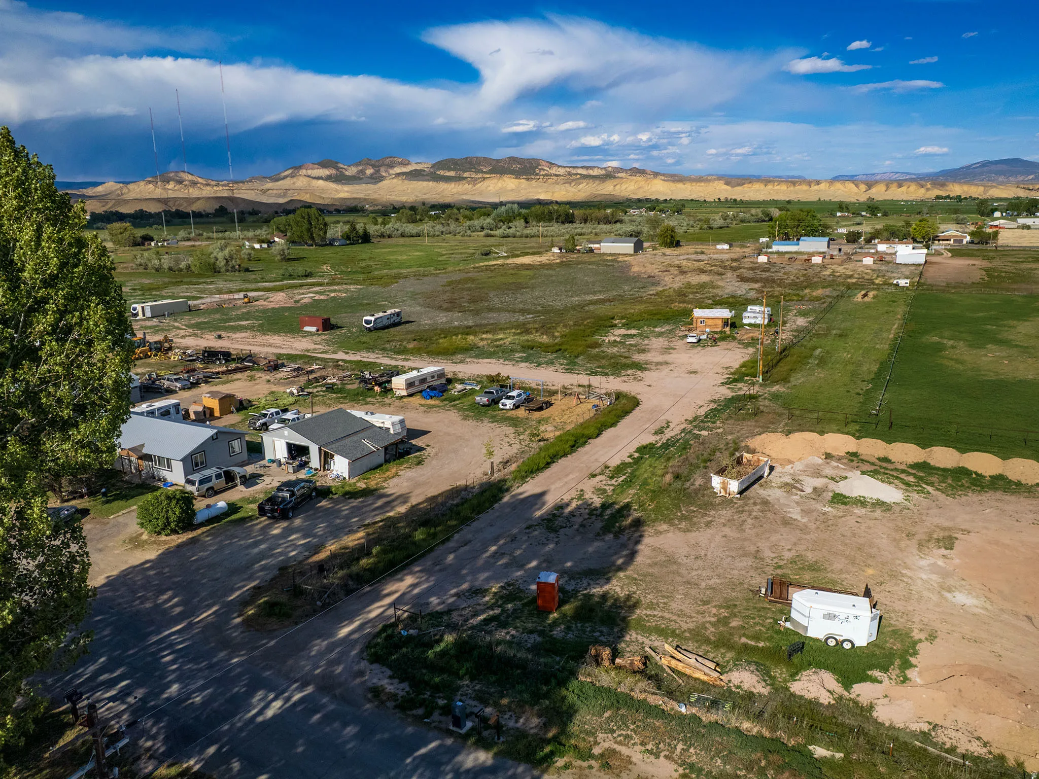 Expansive rural landscape featuring a distant mountain range and a mix of green fields and undeveloped land
