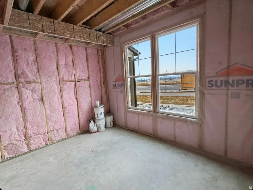 Room under construction featuring two large windows with grid inserts, exposed ceiling joists, and insulated wall framing