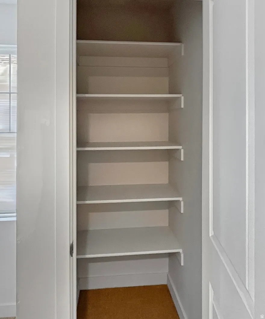 Built-in closet shelving with a light-colored floor, featuring multiple white shelves and white trim