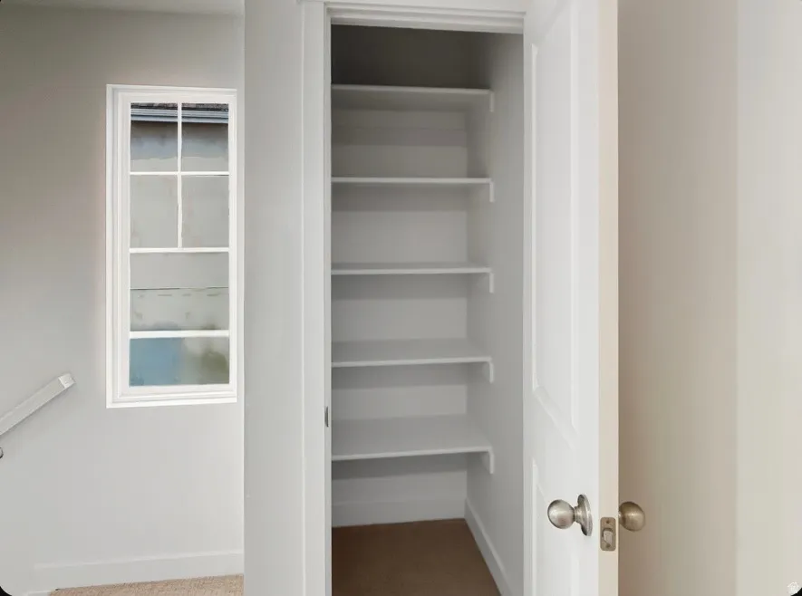 Built-in pantry storage with multiple white shelves, a white paneled door, and brushed nickel hardware