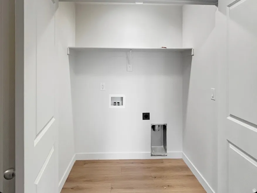 Dedicated utility space featuring a wood-finish flooring, white walls, and a built-in shelf