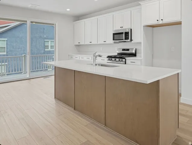 Kitchen featuring a large central island with light wood-finish paneling and a light-toned countertop