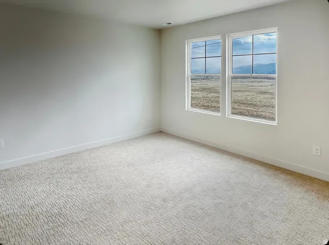 Spacious room featuring neutral carpeting and white baseboards