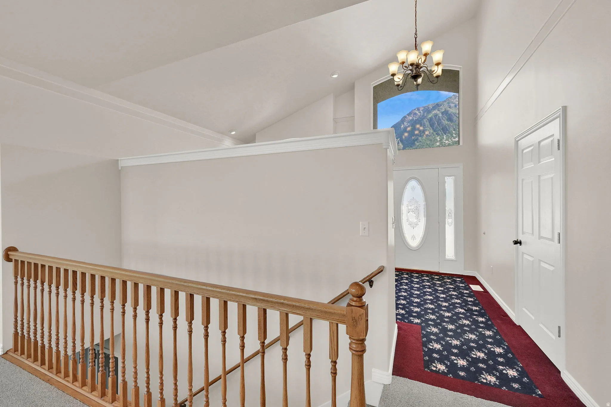 Vaulted ceiling entry with a decorative front door and sidelights