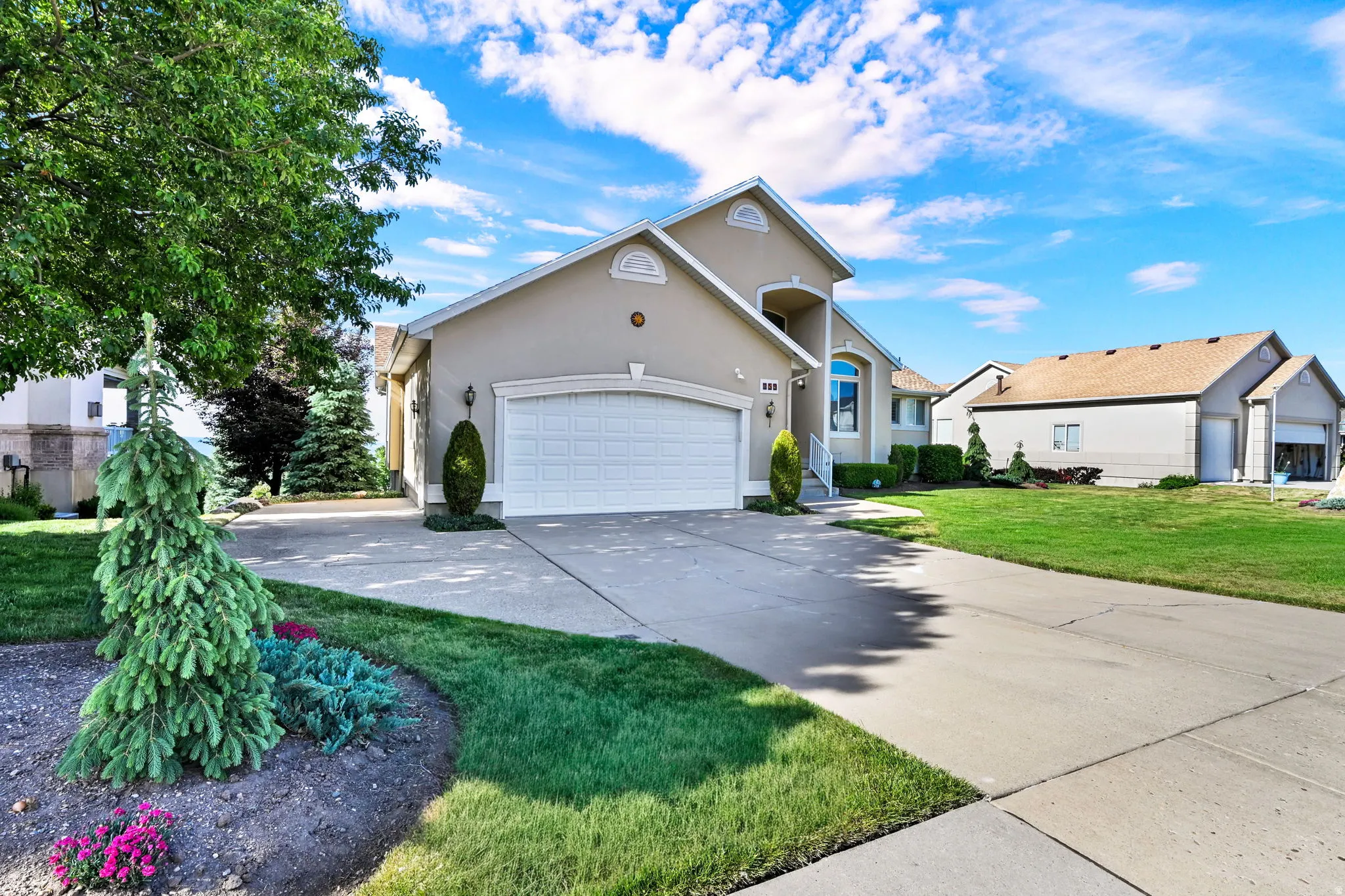 Stucco exterior property featuring a two-car garage, concrete driveway, and an arched entry