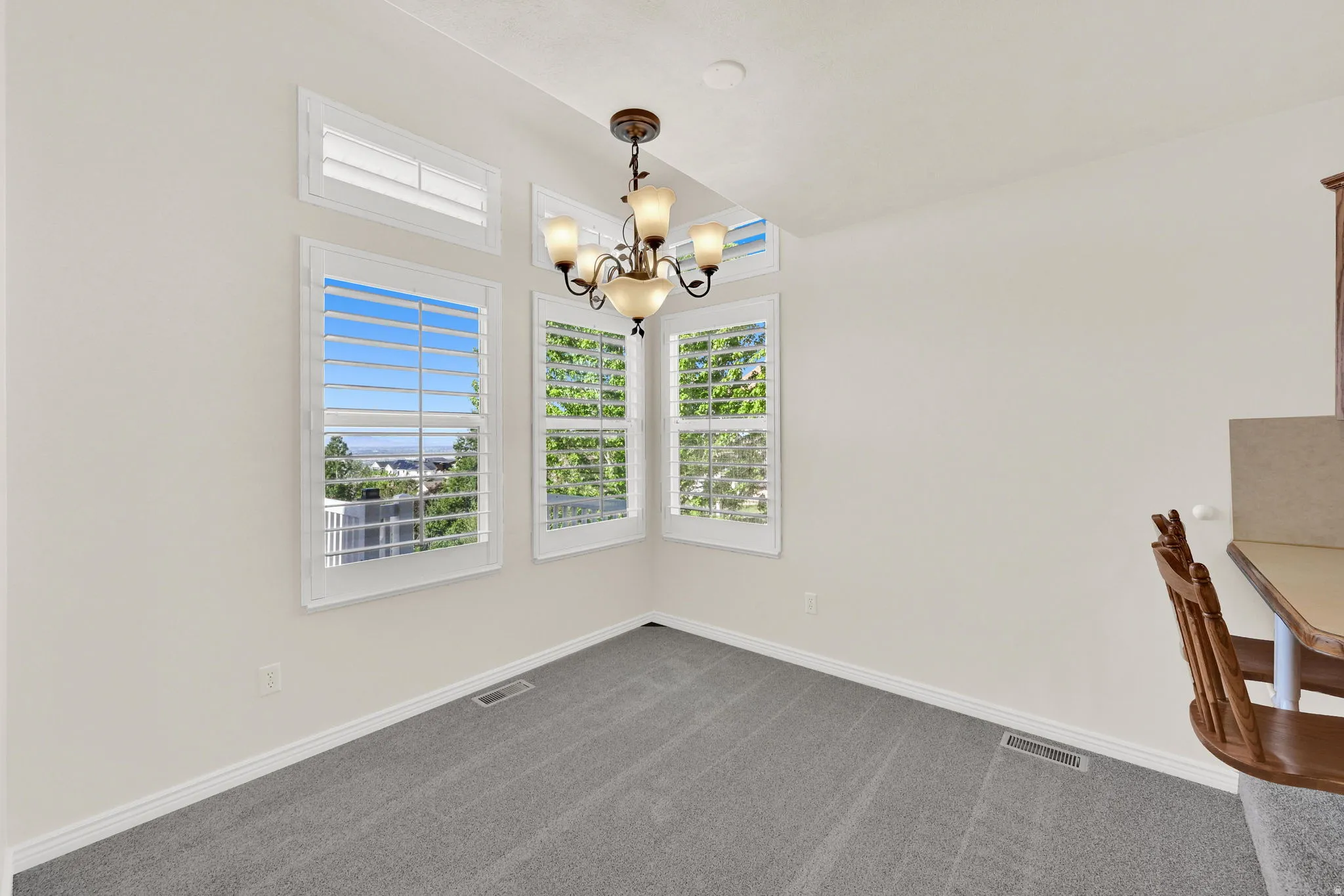 Dining area featuring a classic chandelier and multiple windows with plantation shutters