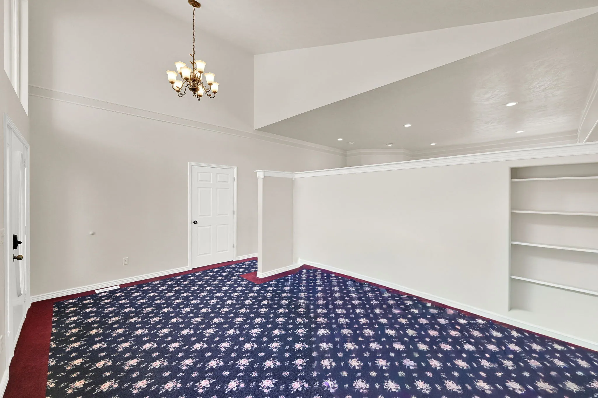 Vaulted ceiling with an overhead chandelier and recessed lighting
