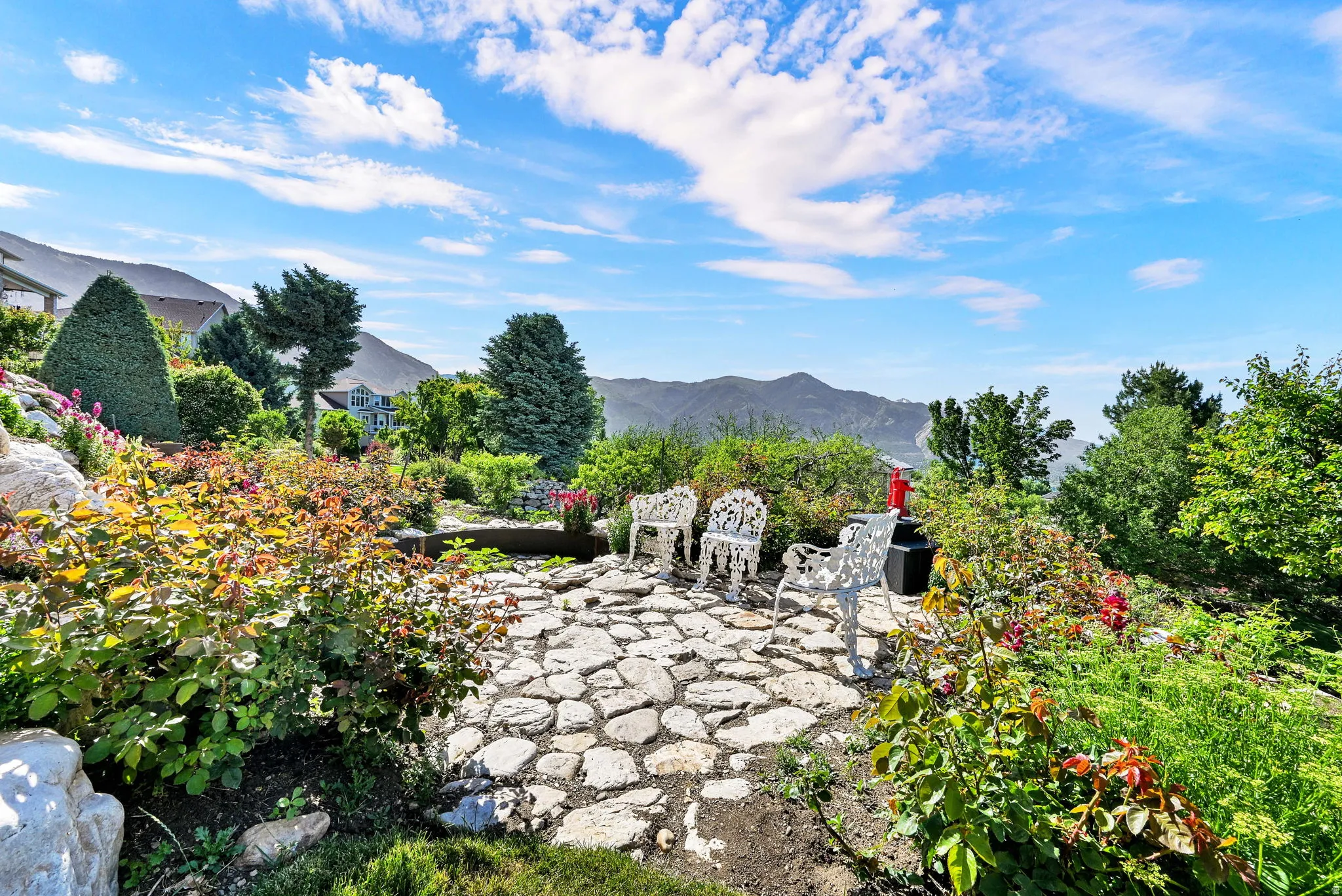 Expansive flagstone patio area surrounded by mature landscaping and terraced gardens