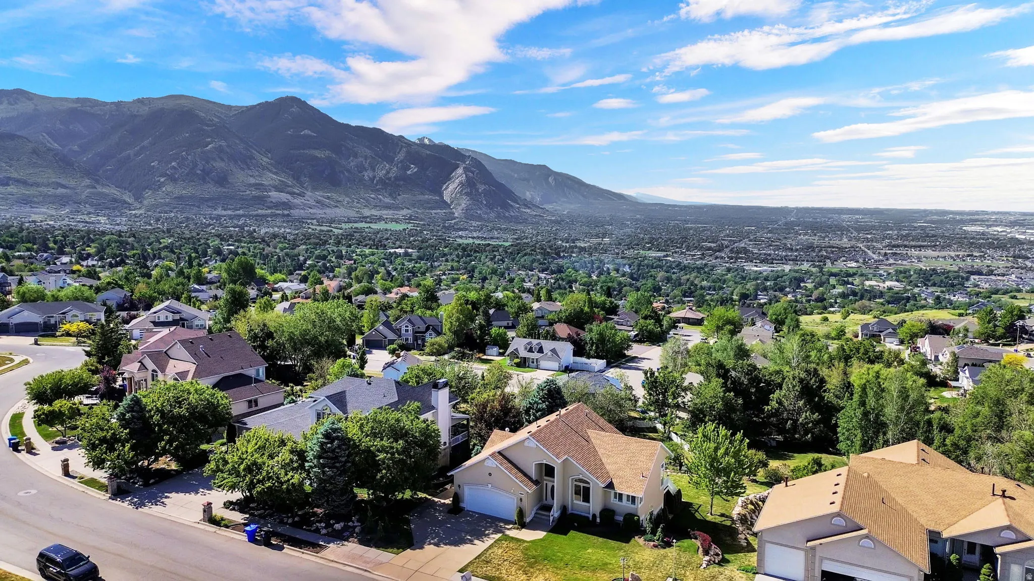 Expansive mountain range backdrop framing a residential area with mature trees and a curving streetscape