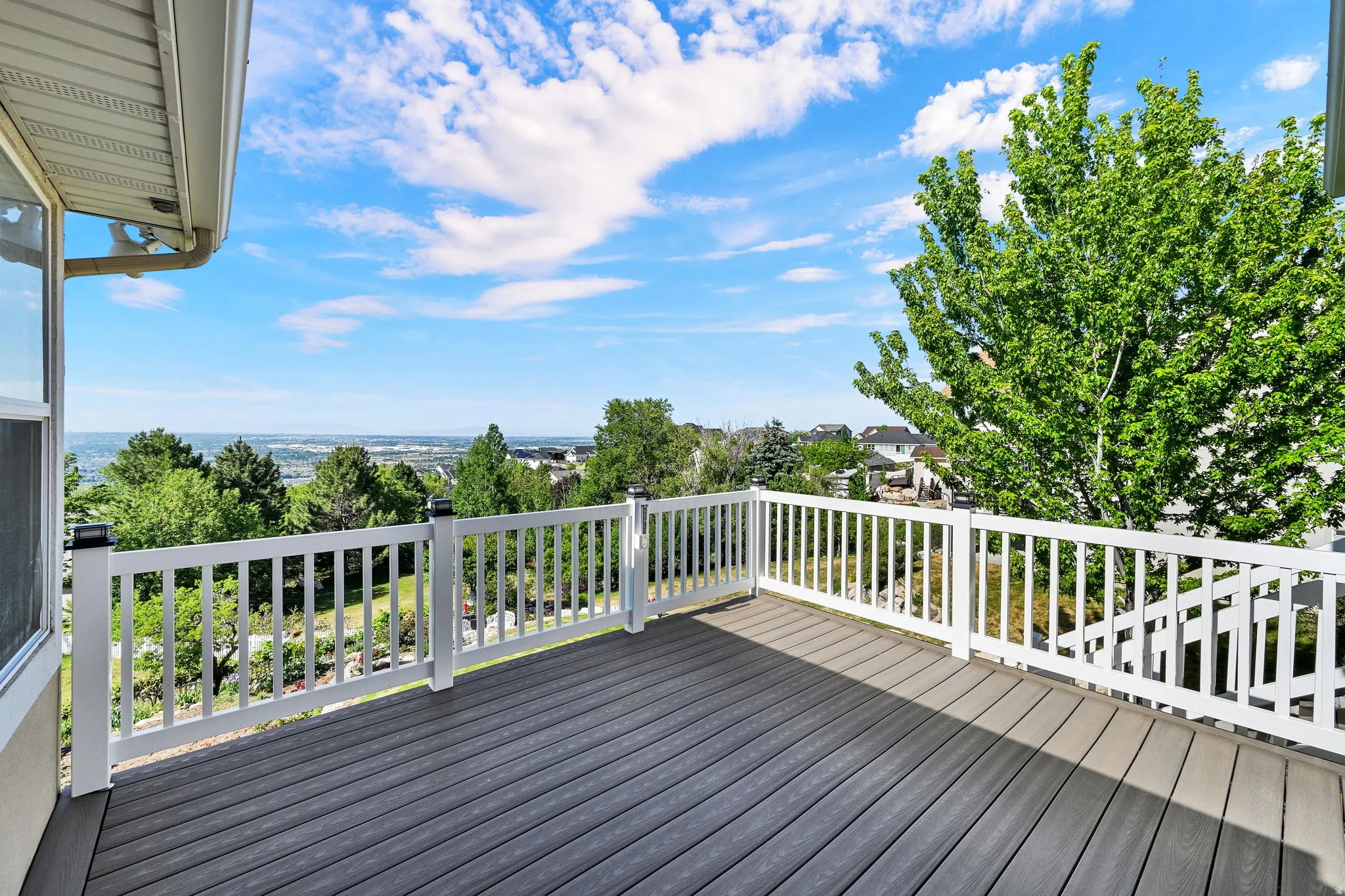 Spacious outdoor deck featuring gray composite decking, white railing, and a broad landscape vista