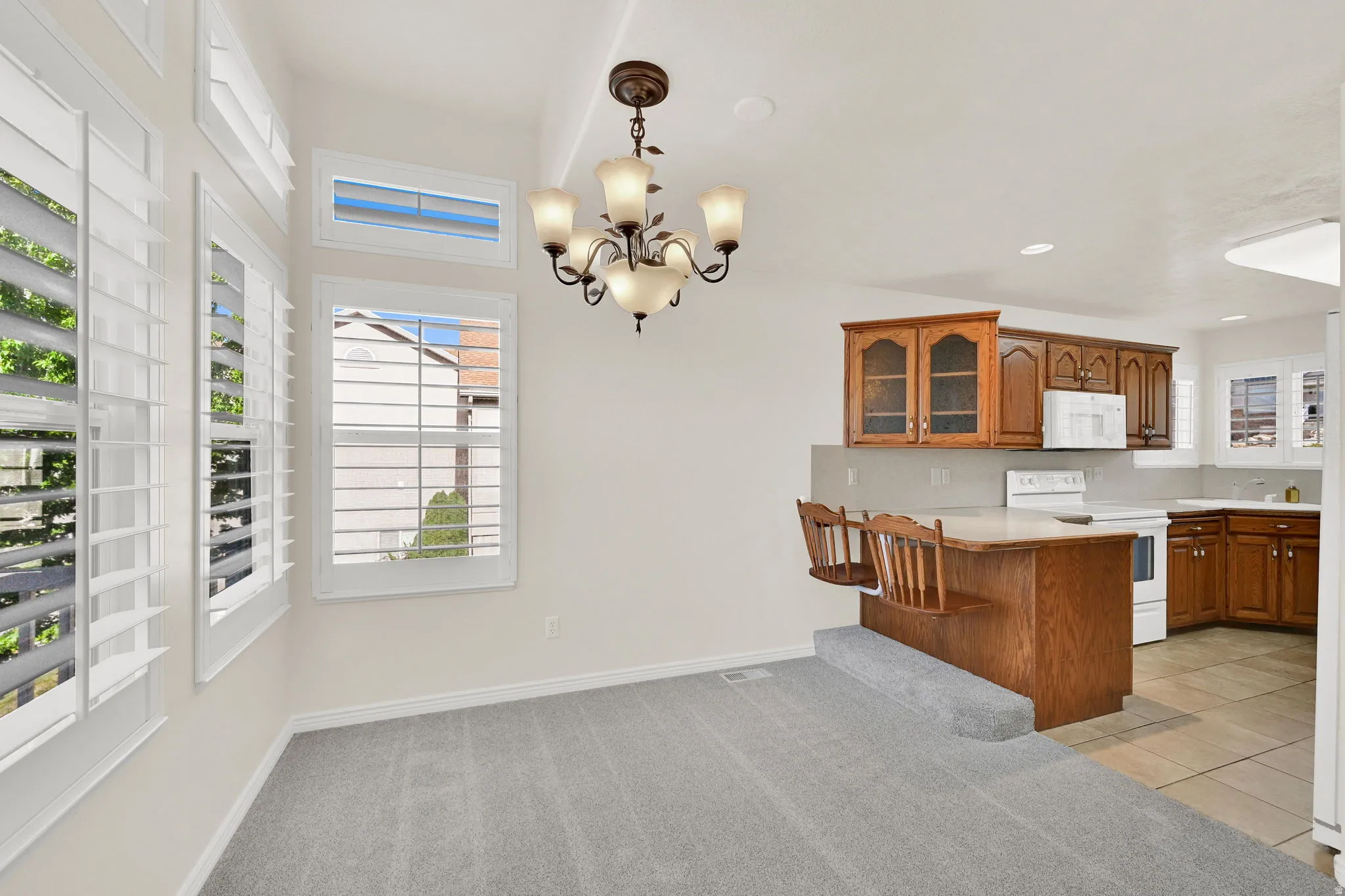 Dining area with white shuttered windows, a chandelier, and plush grey carpeting