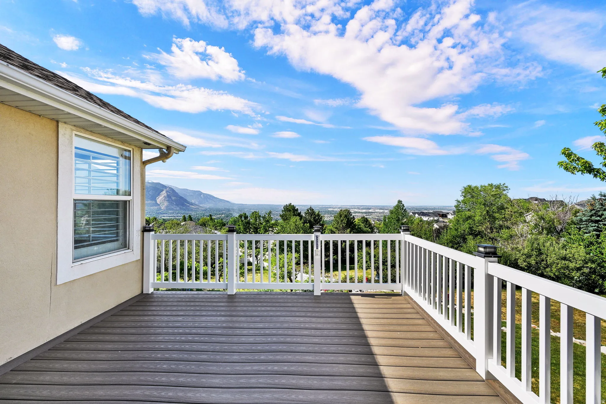 Spacious outdoor deck featuring composite decking, white baluster railing, and an expansive mountain backdrop