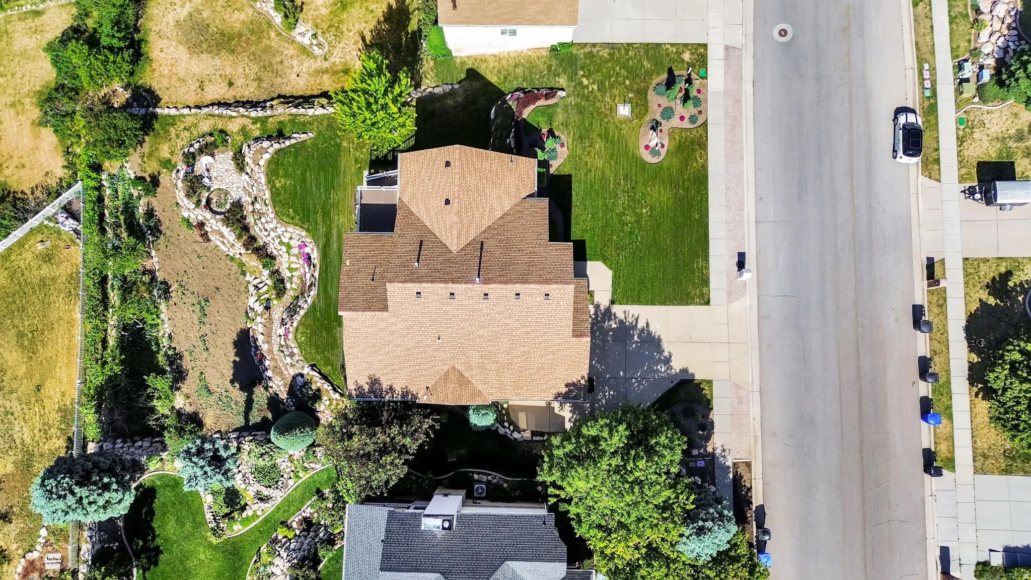 Aerial perspective showcasing a property with a distinct, terraced landscape design featuring a winding rock garden