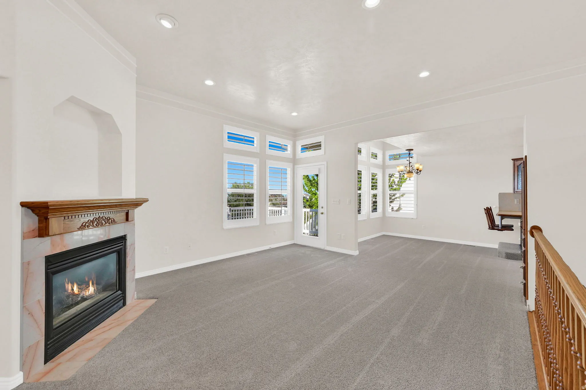 Living area featuring a gas fireplace with a marble surround and wood mantel, recessed lighting, and crown molding
