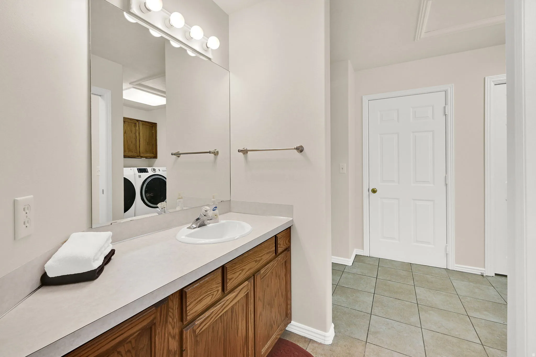 Bathroom vanity featuring wood cabinetry, a light-colored countertop, and an integrated sink with a chrome faucet
