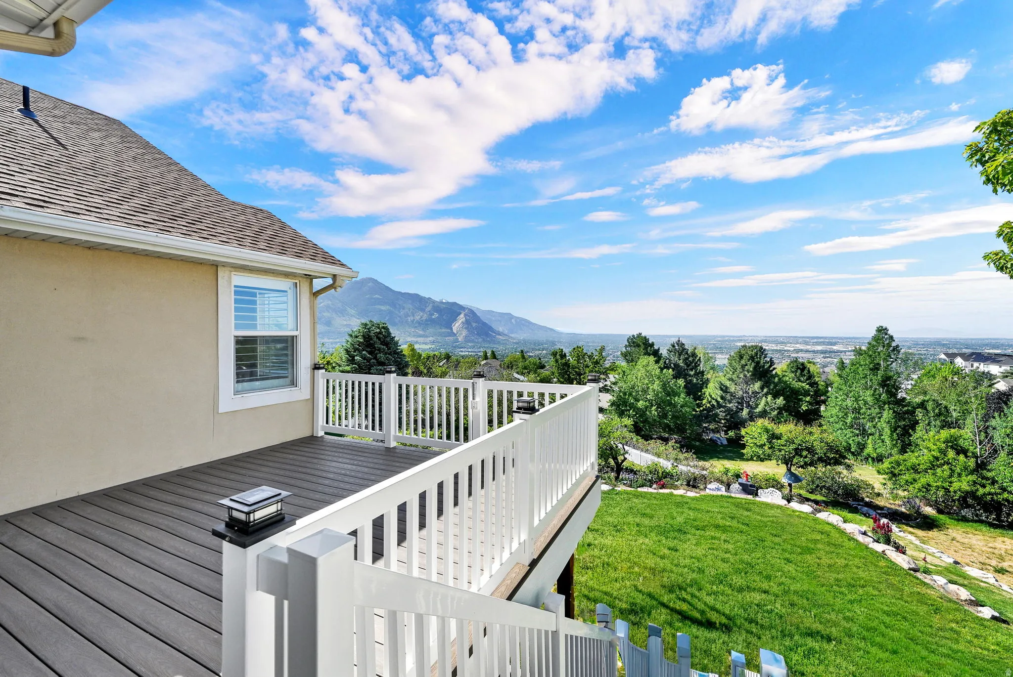 Elevated outdoor deck featuring composite decking, white railing, and a mounted solar light