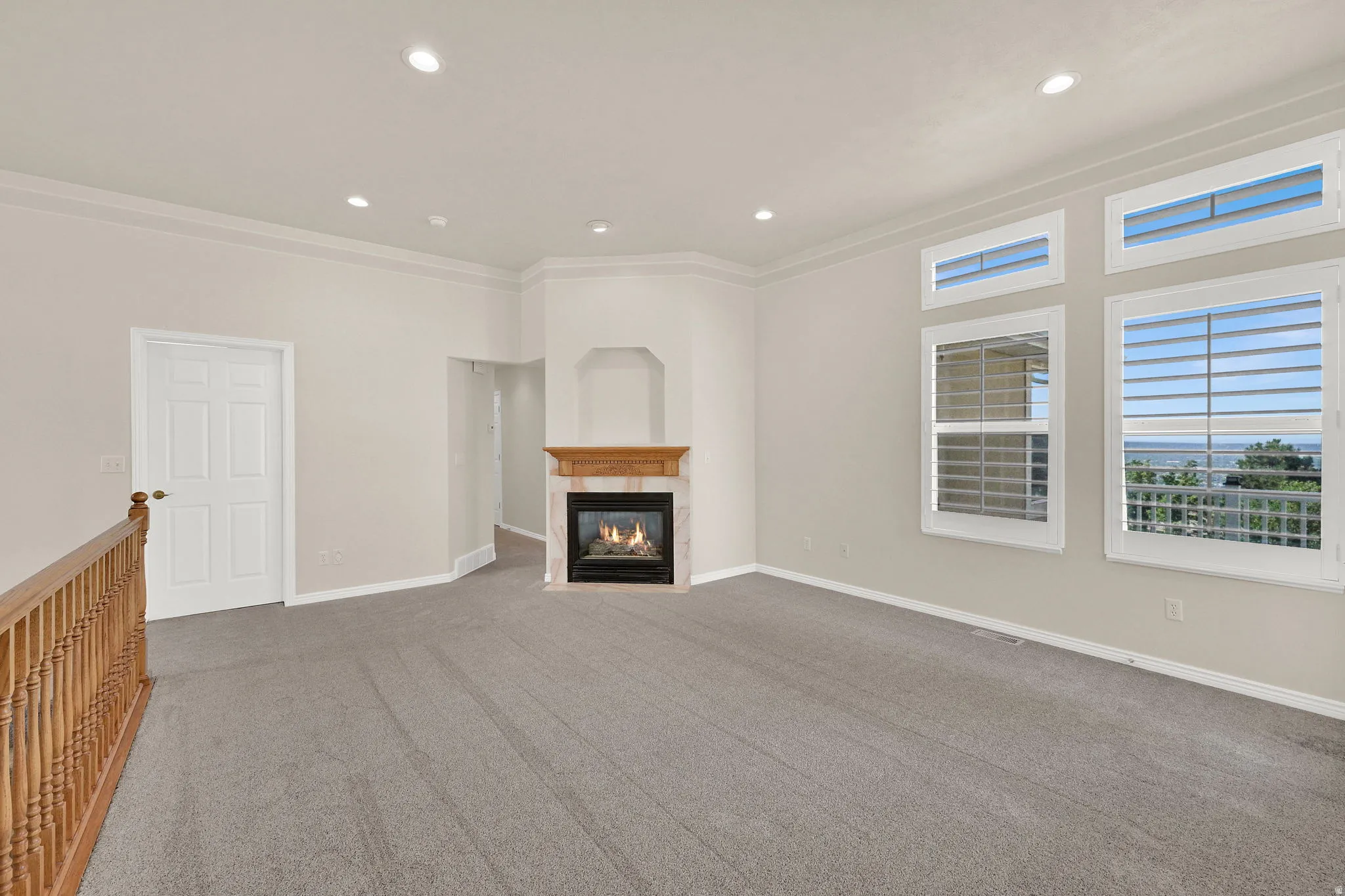 Living area featuring a gas fireplace with a wood mantle, recessed lighting, and grey carpet