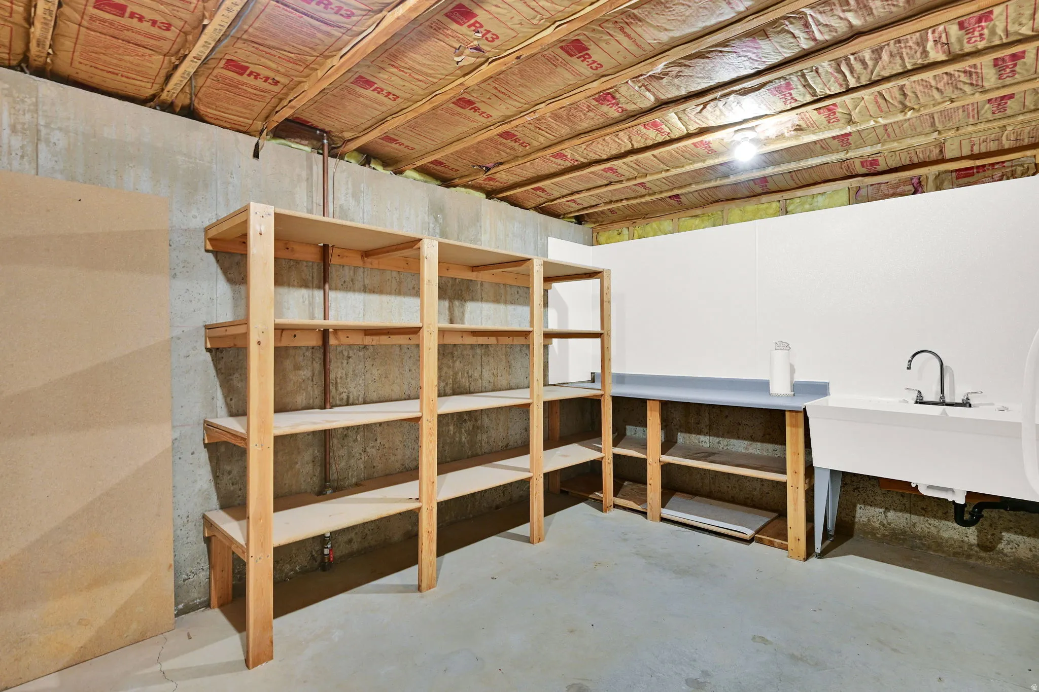 Unfinished basement space featuring concrete foundation walls and exposed ceiling joists with insulation