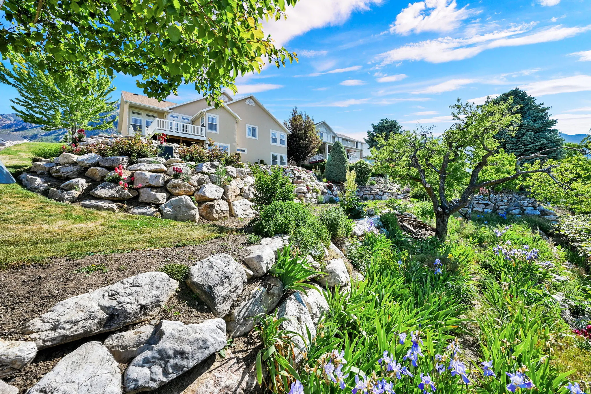 Terraced landscaping with natural rock retaining walls, mature trees, and established plantings