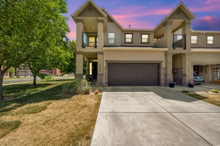Two-story exterior with a covered balcony, stone accents, and a two-car attached garage