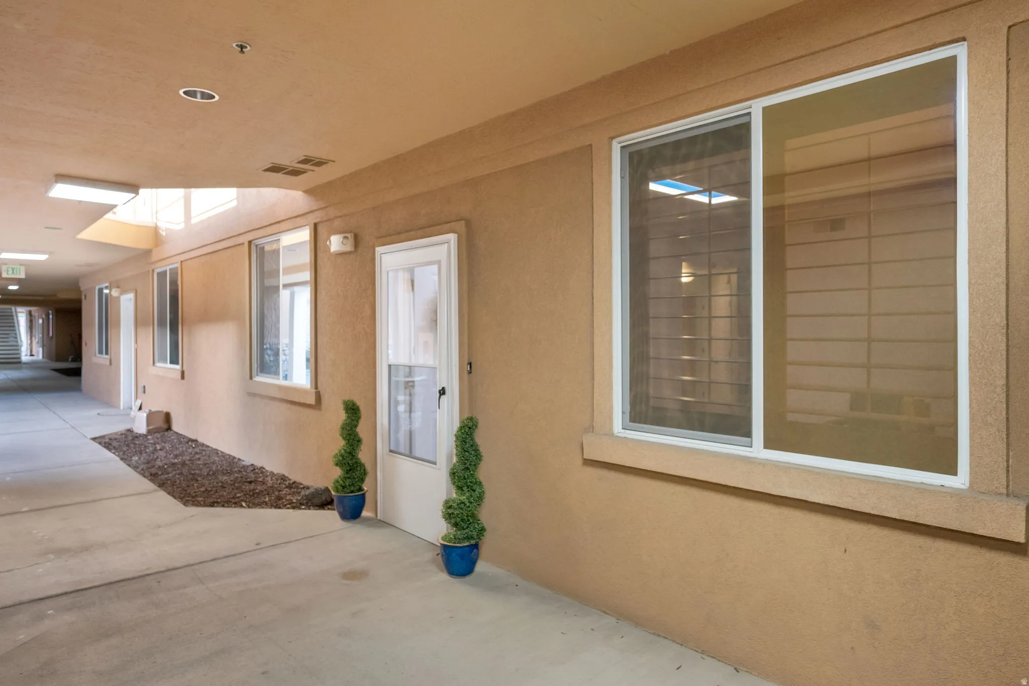Covered exterior walkway featuring stucco walls and concrete flooring