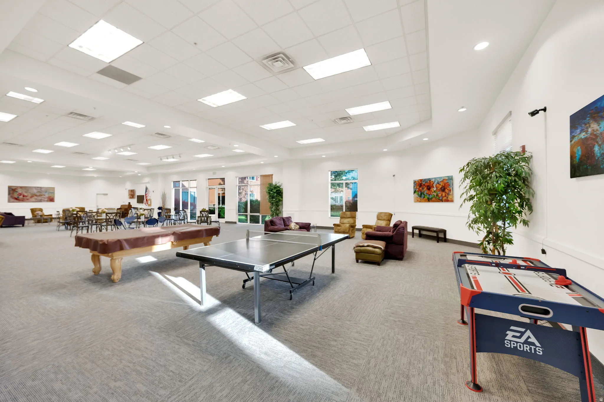 Spacious multi-purpose room featuring neutral carpeting, recessed ceiling lighting, and large windows