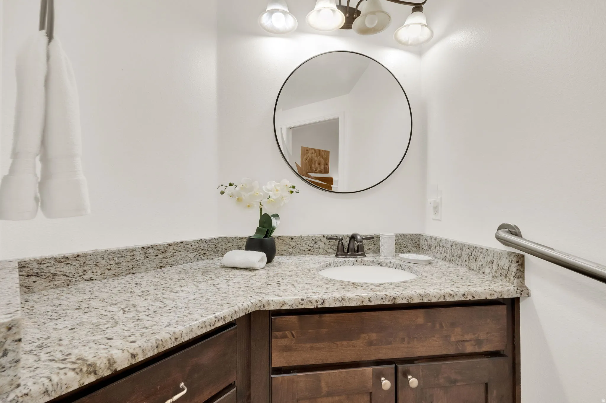 Bathroom vanity featuring an undermount sink, granite countertop, and dark wood-finish cabinetry