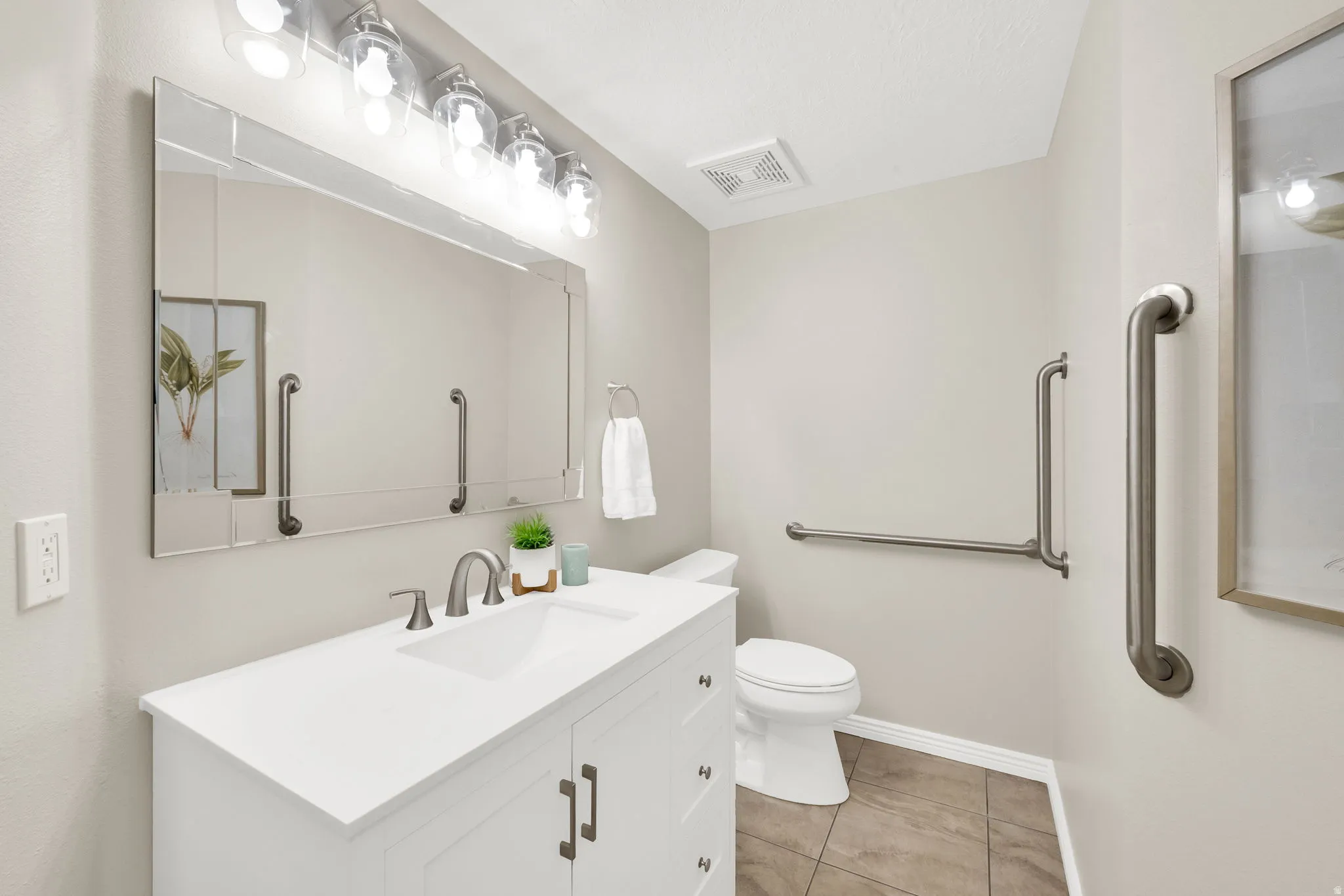 Bathroom featuring a white vanity with an integrated sink, brushed nickel faucet, and a rectangular mirror