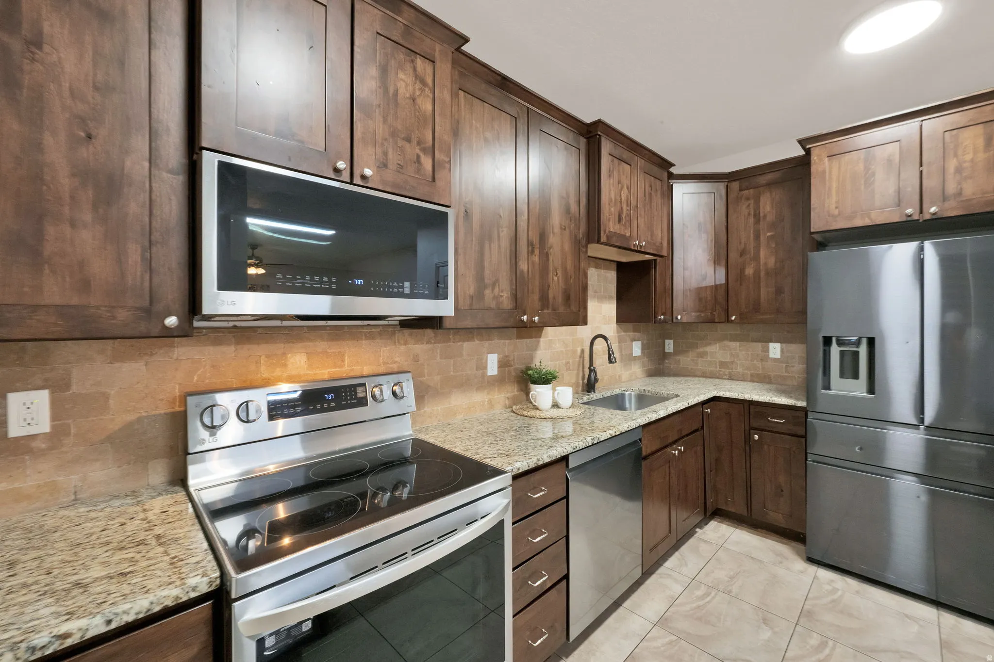 Kitchen featuring wood cabinetry, light granite countertops, and a tiled backsplash