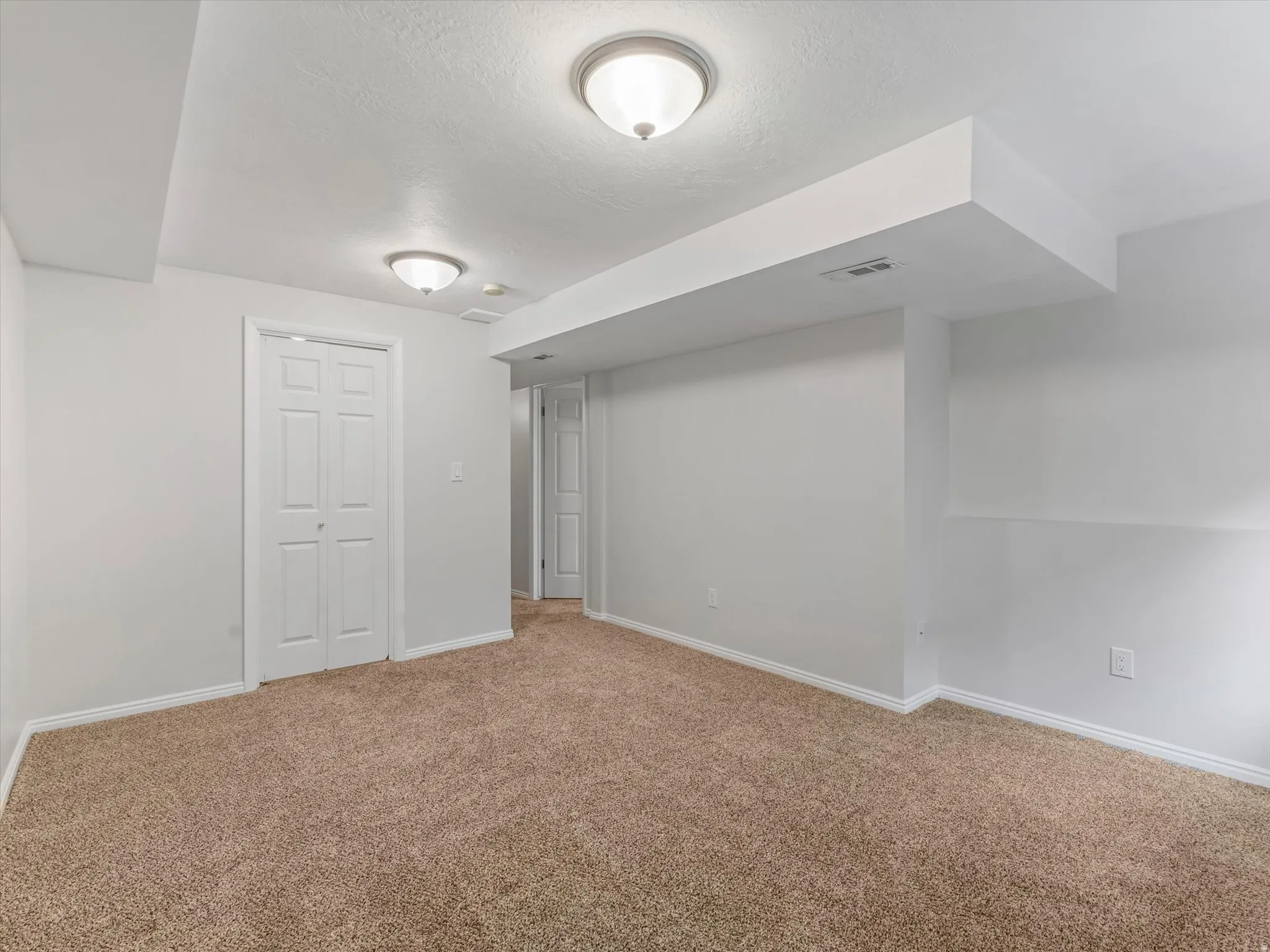 Neutral-toned carpeting paired with white walls, baseboards, and ceiling