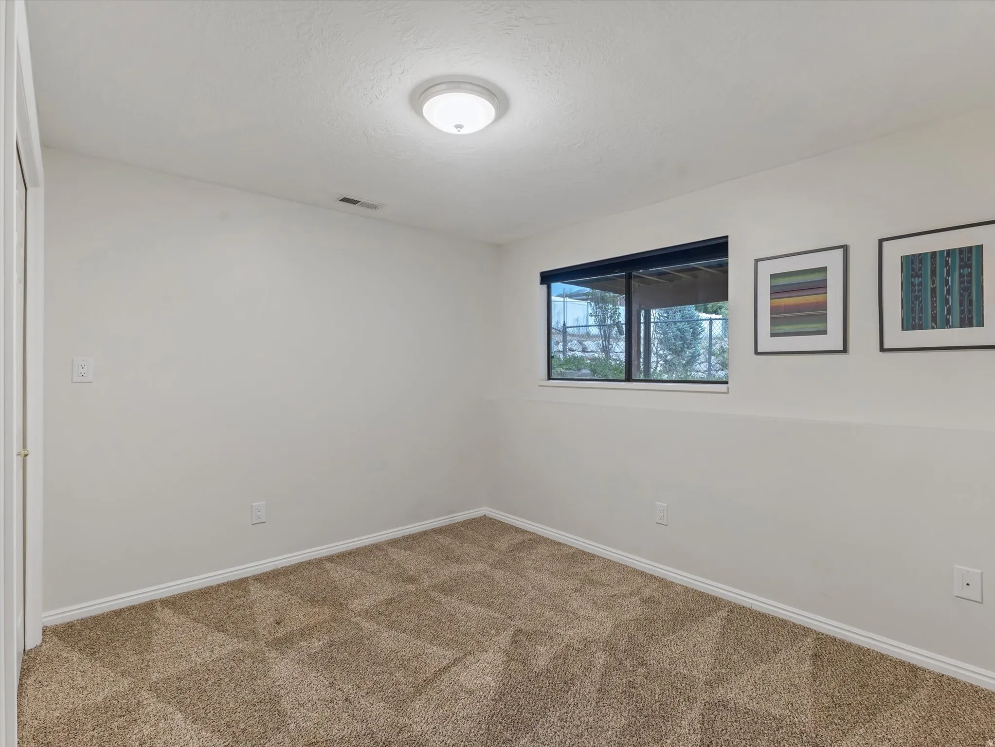 Carpeted room featuring a single window, white walls, and a flush-mount ceiling light