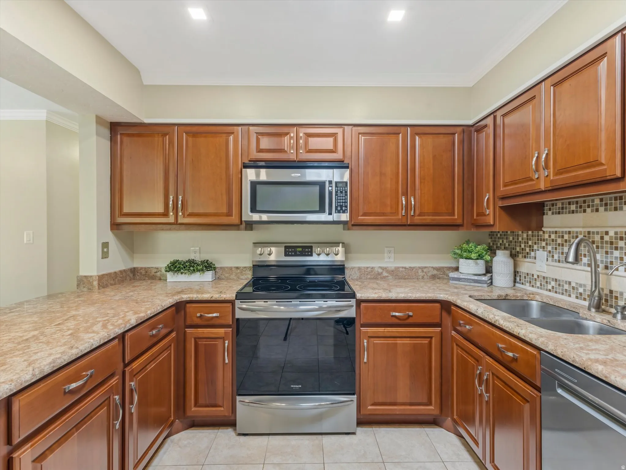 U-shaped kitchen featuring wood cabinetry, stone-look countertops, and a mosaic tile backsplash