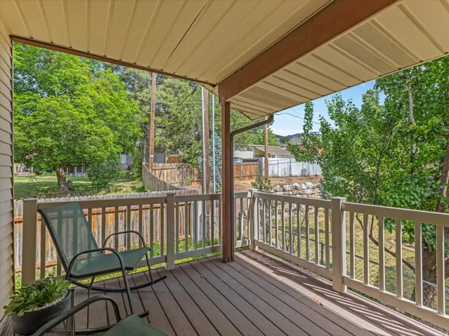 Covered porch featuring a wood-finish deck and white railing