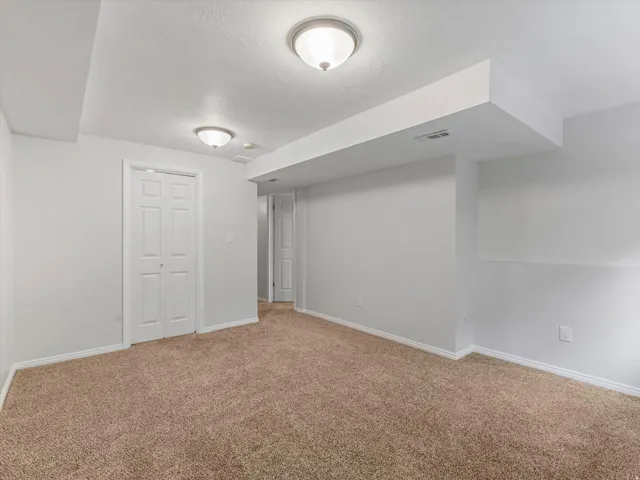 Neutral-toned carpeting paired with white walls, baseboards, and ceiling