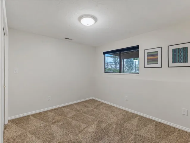 Carpeted room featuring a single window, white walls, and a flush-mount ceiling light