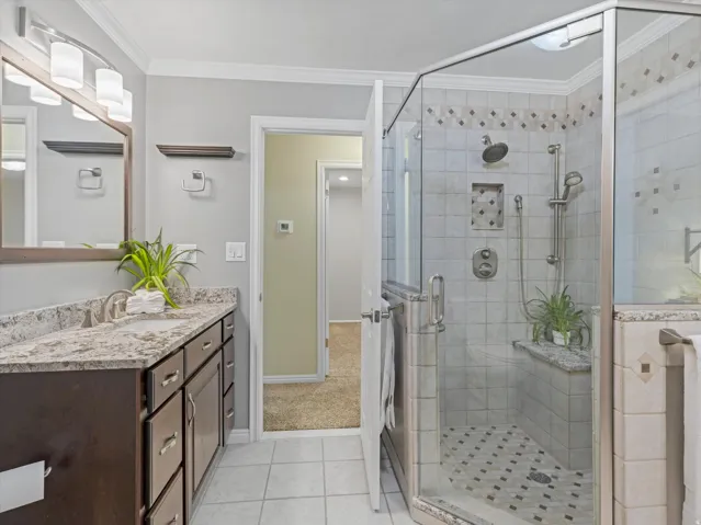 Bathroom featuring a glass-enclosed shower with tile surround, built-in shelving, and a bench