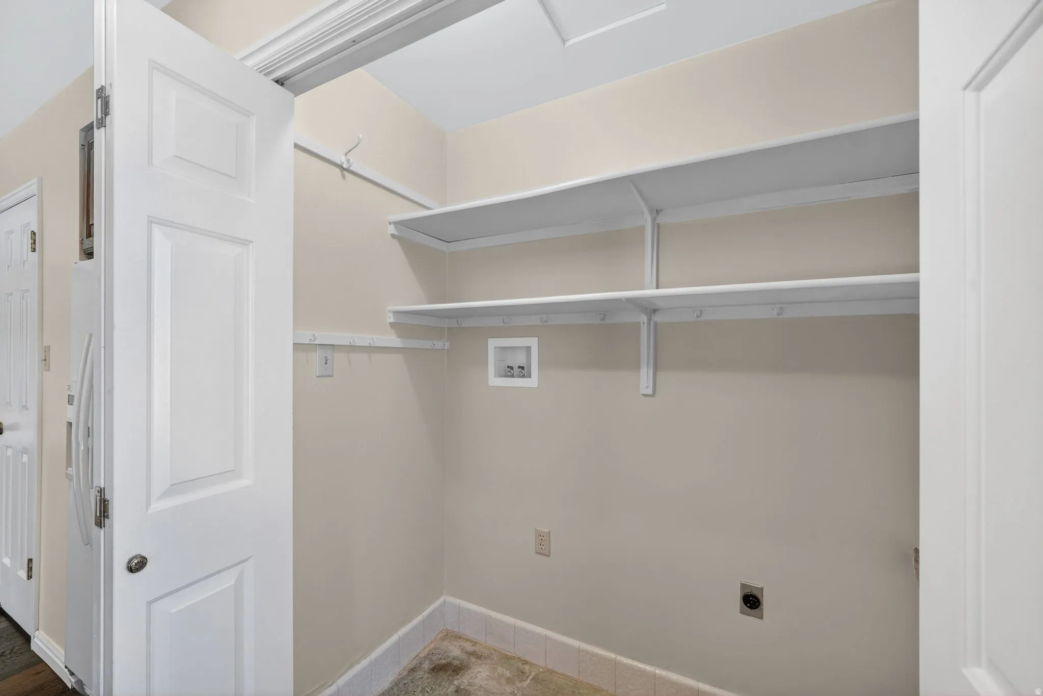 Dedicated laundry area featuring integrated shelving, light-toned wall paint, and floor-level electrical outlets