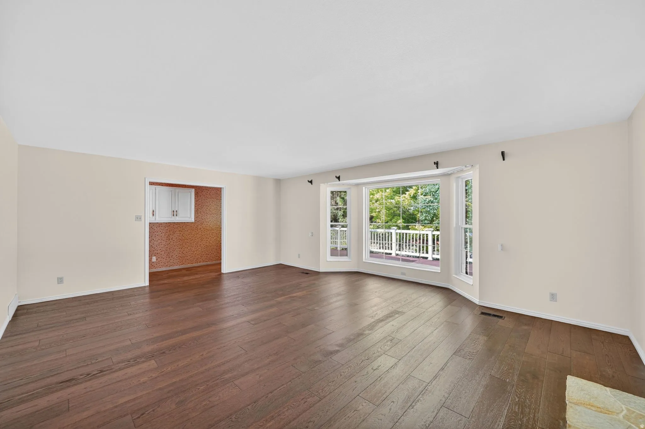 Expansive living area featuring rich wood-finish flooring and neutral wall tones