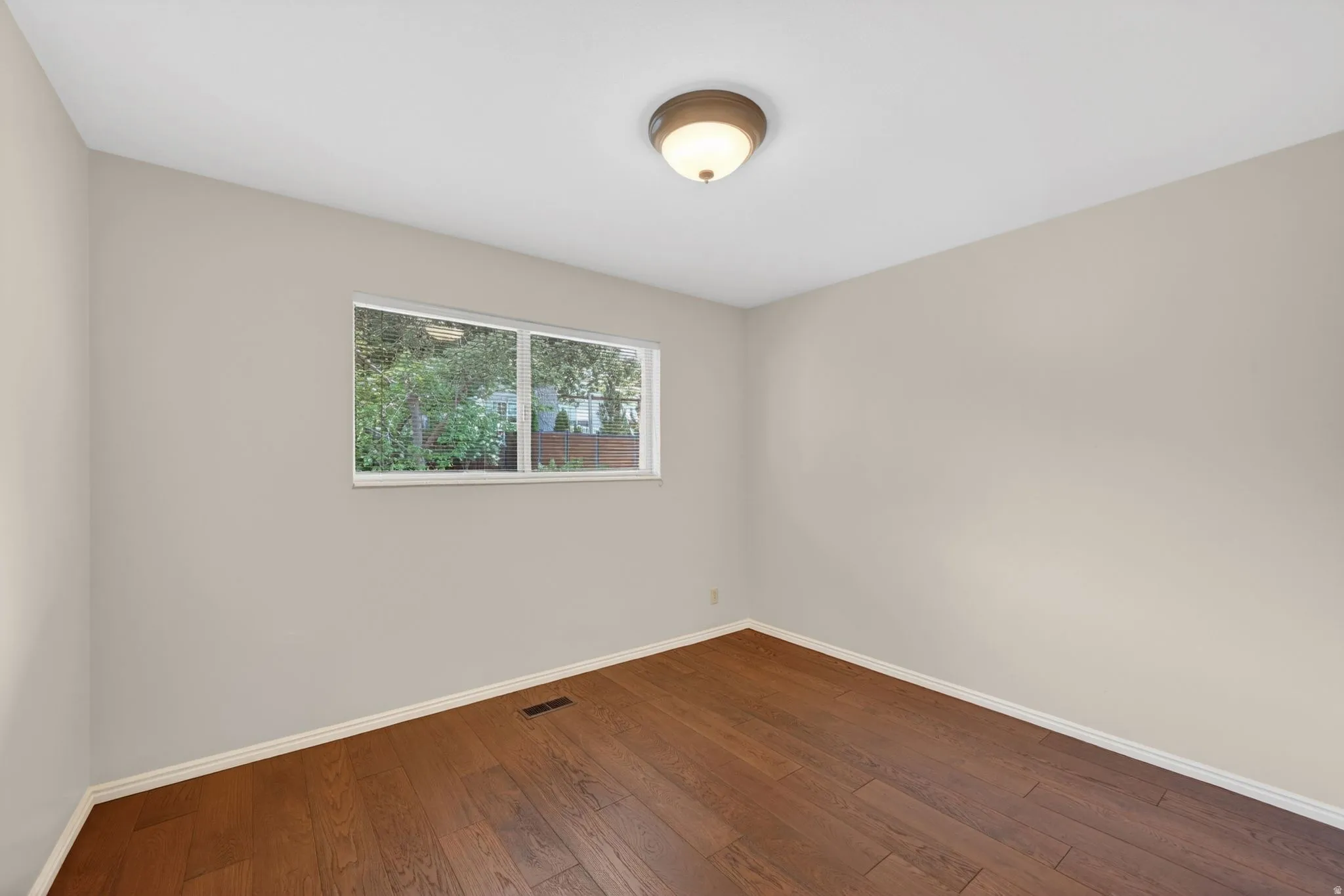 Room featuring wood-finish flooring, neutral wall tones, and white baseboards