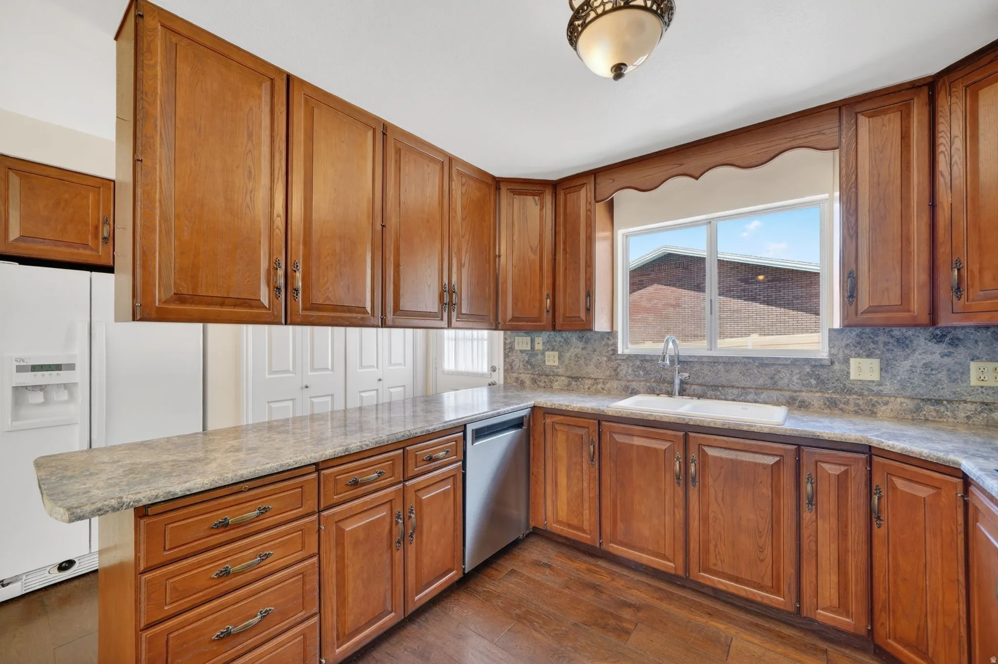 Kitchen featuring wood-finish cabinetry, stone-look countertops, and a complementary backsplash