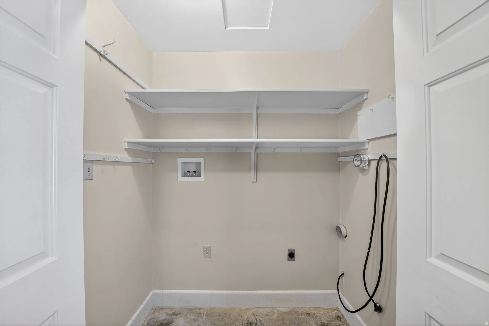 Dedicated utility room featuring two levels of built-in shelving, plumbing hookups, electrical outlets, and a tiled floor border
