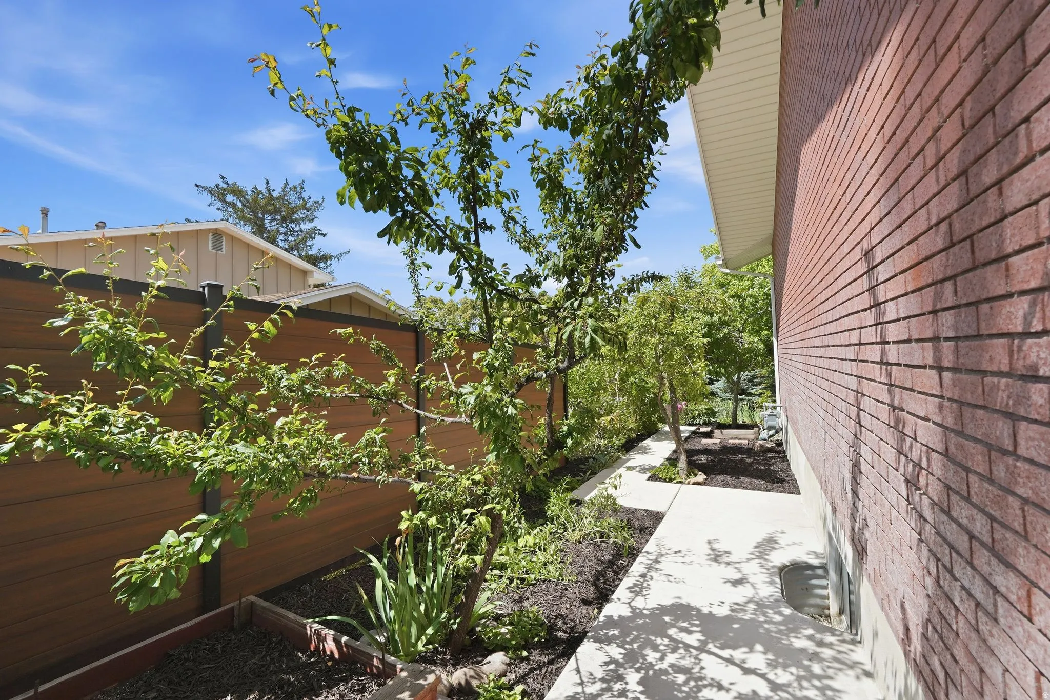 Brick exterior with a concrete walkway and mature landscaping